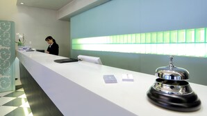 Um balcão de recepção com design moderno, um sino e uma janela com vidro esverdeado.