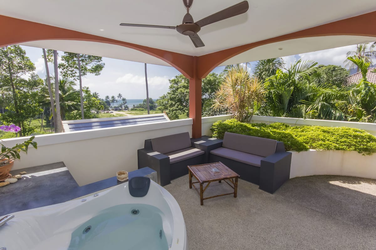 Un espacio exterior techado con un jacuzzi, asientos y vistas al paisaje.