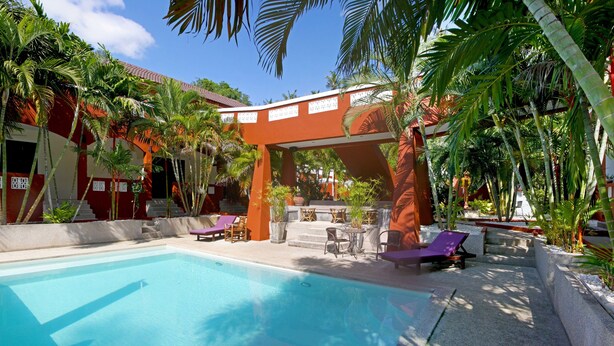 A pool area with a clear blue pool, surrounded by palm trees and a covered walkway. - Sallamai Resort (Koh Samui)