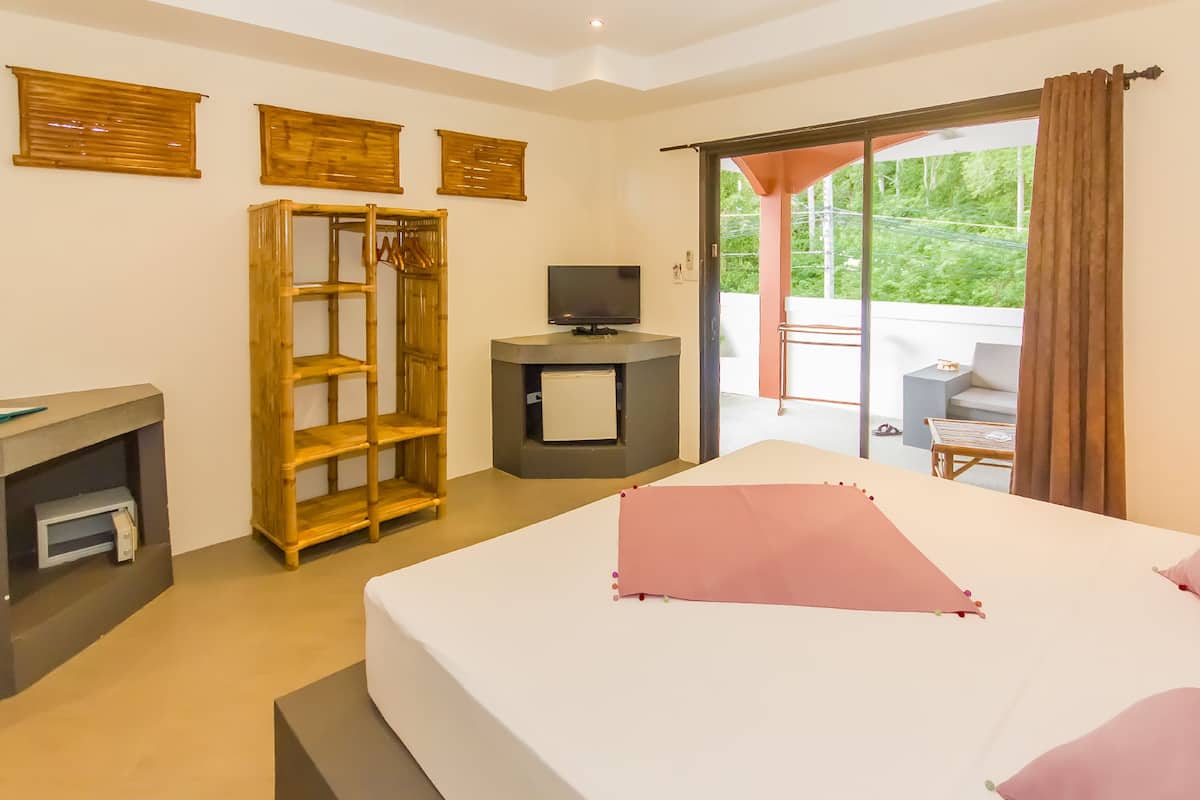 Un dormitorio con cama, televisor, armario y balcón con mesa y sillas.
