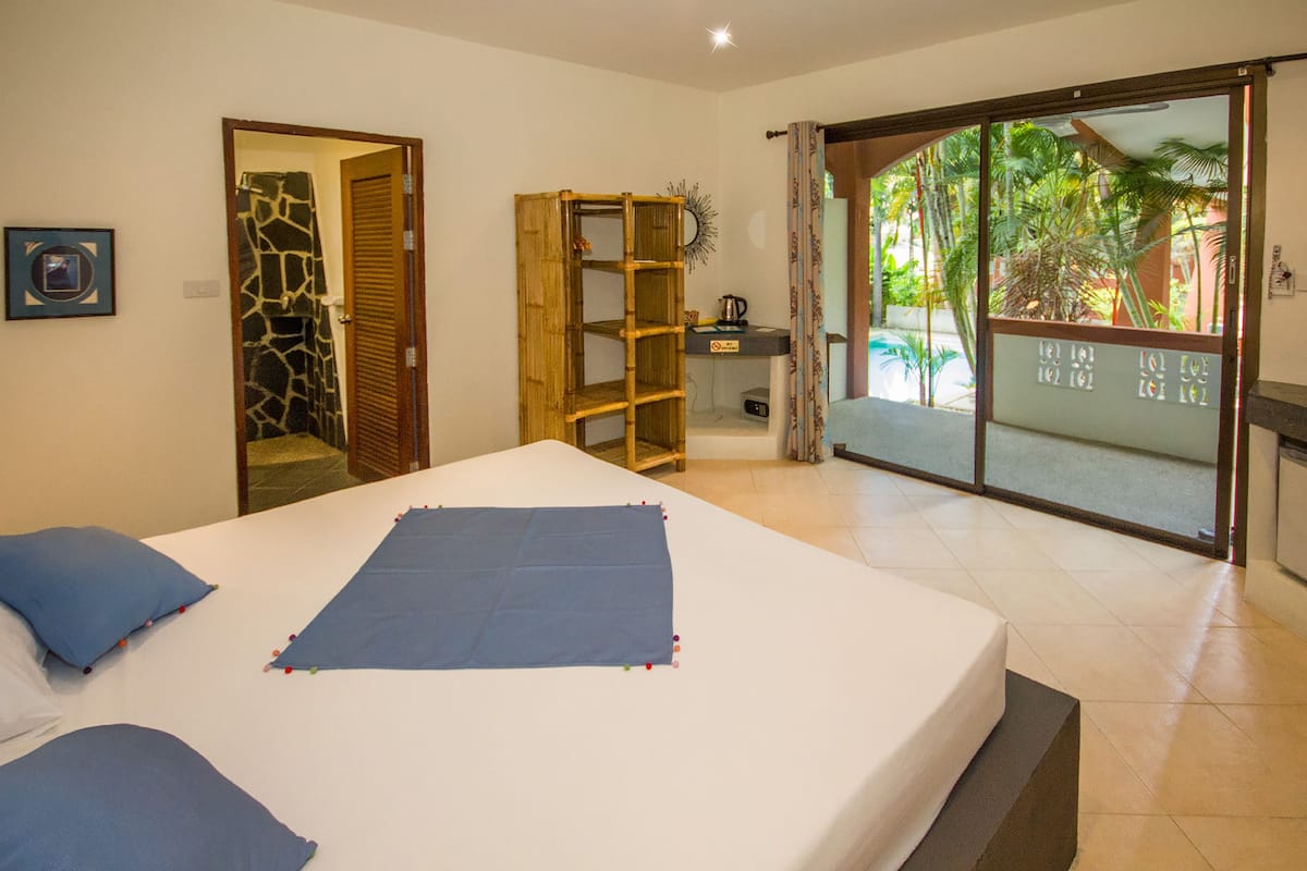 Un dormitorio con cama, armario, mesita y vistas al exterior.