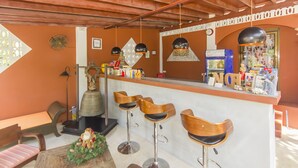A bar area with wooden stools, a counter with various items, and a decorative wall. - Sallamai Resort (Koh Samui)