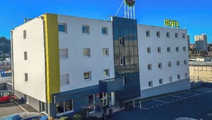 Een modern hotelgebouw met een opvallend B&B bord, meerdere ramen en een parkeerplaats.