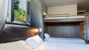 Een kamer met twee bedden, een stapelbed, een raam met uitzicht op groen en een airconditioning.