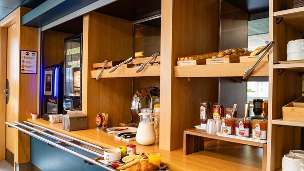 Een ontbijtbuffet met een koffieapparaat, broodrooster en diverse ontbijtartikelen.