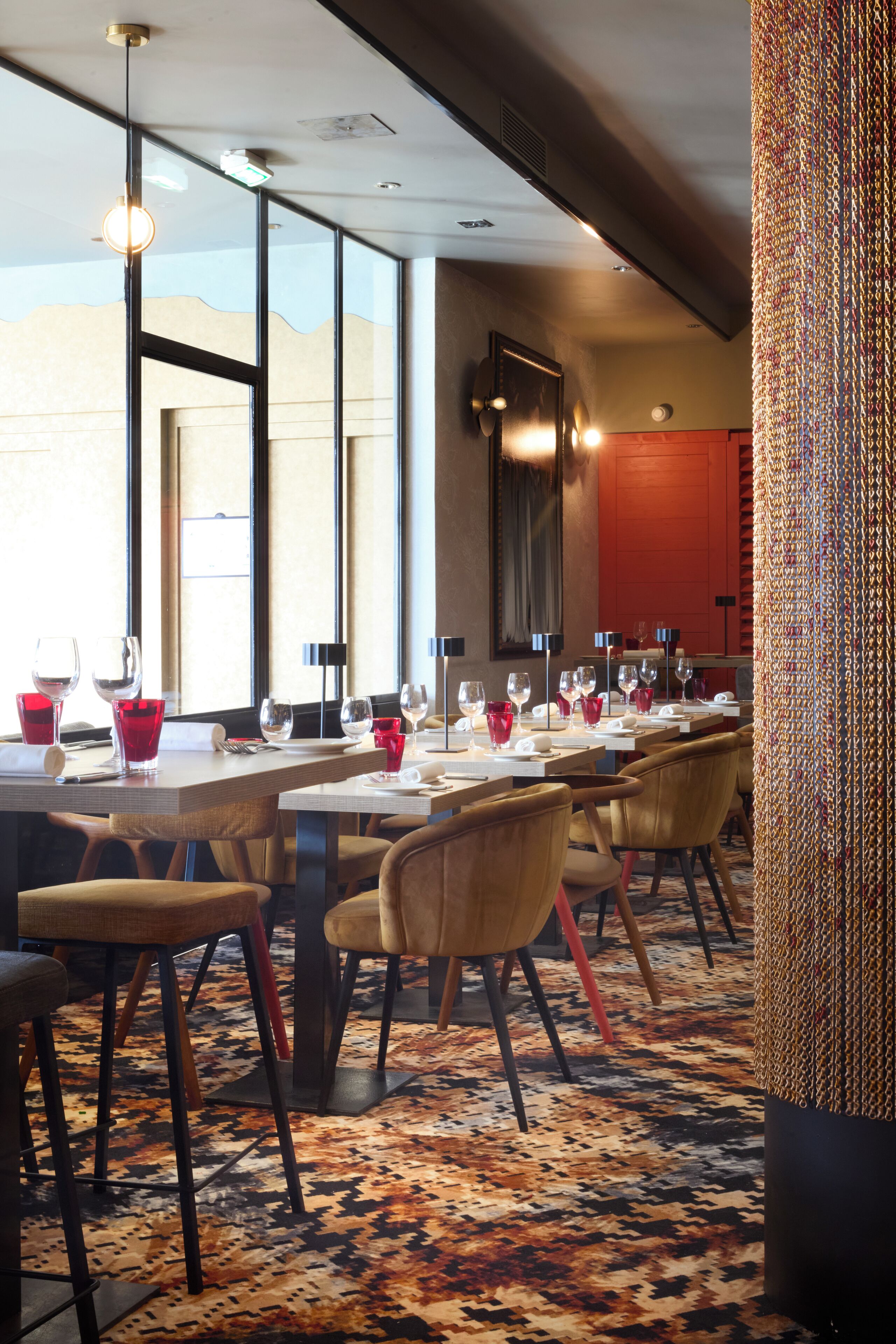 A restaurant with long tables, chairs, and a patterned carpet.