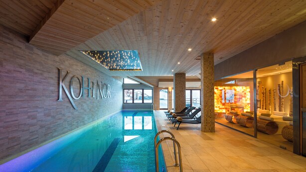 Piscina interna com teto de madeira e placa com o nome visível.