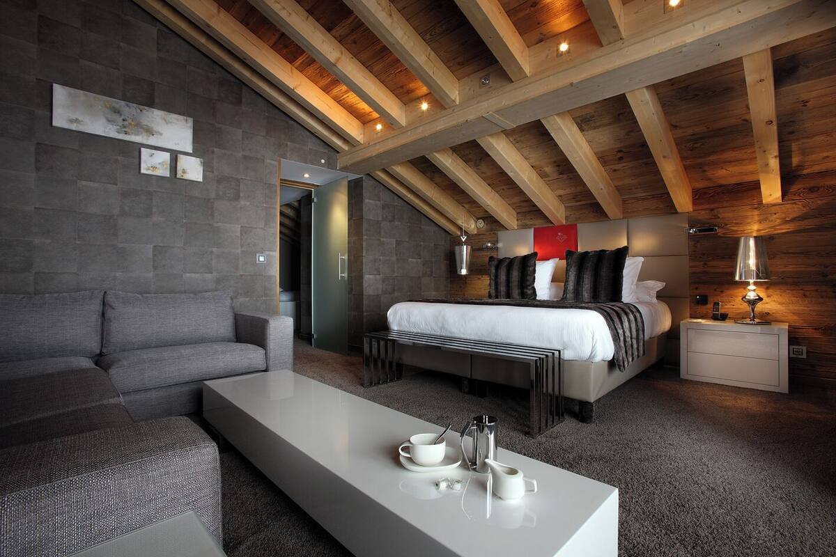 Un dormitorio moderno con una cama grande, un sofá, una mesa de centro y una mesita de noche.