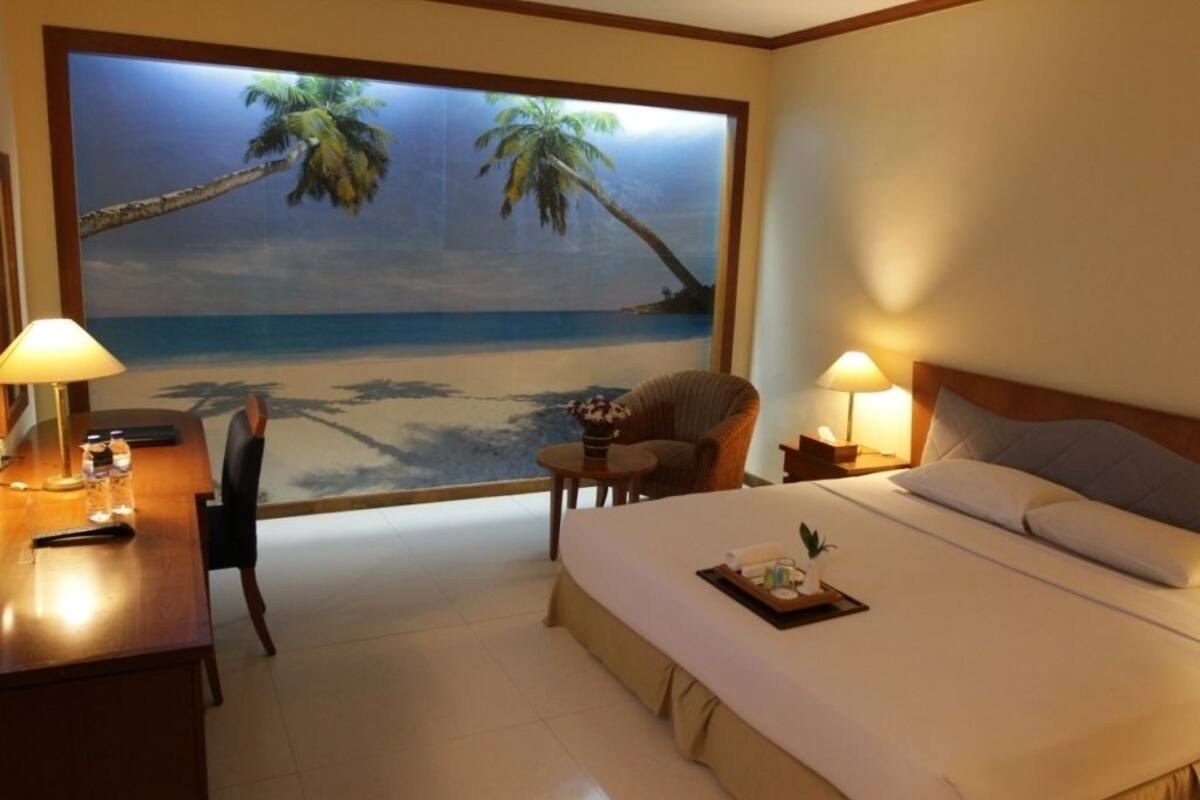 Une chambre d’hôtel avec une grande fenêtre, un lit, un bureau et une chaise.