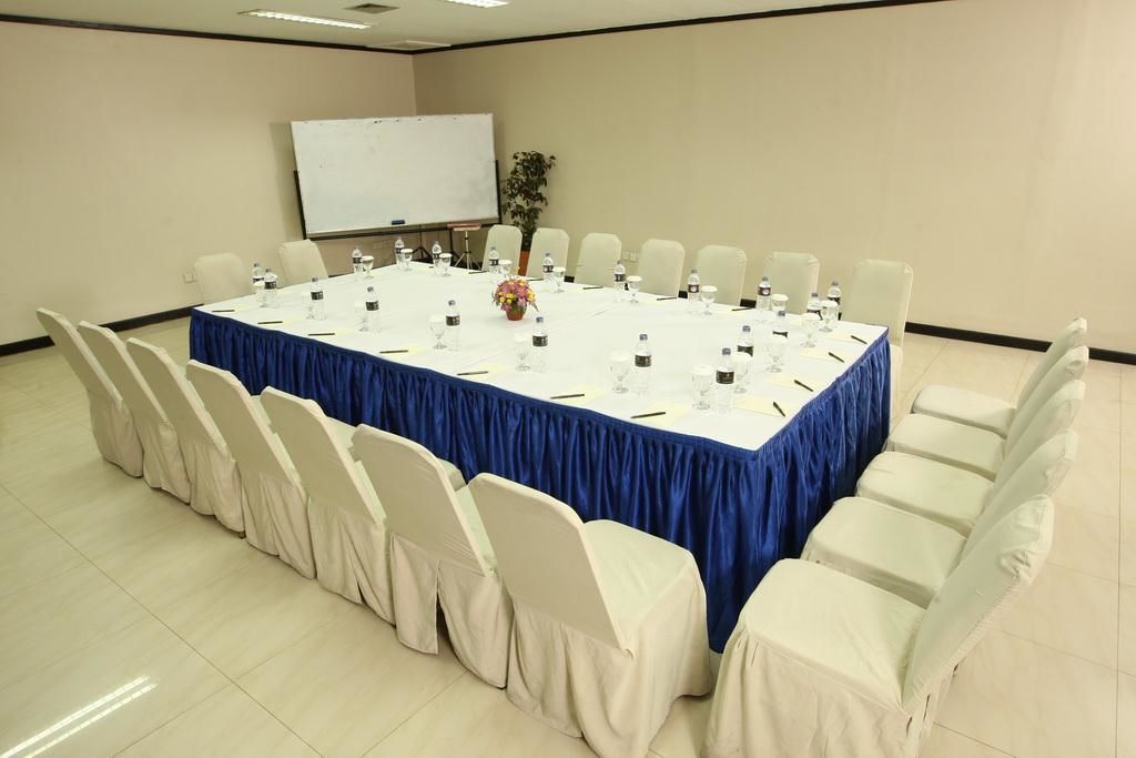 A conference room with a large table, white chairs, and a whiteboard.