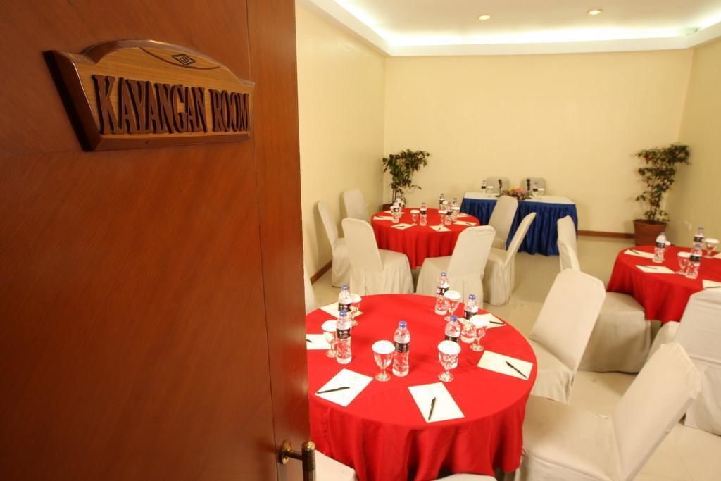 A conference room with round tables, each covered with a red tablecloth and white chairs.