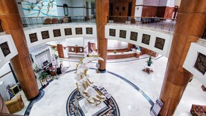 A spacious lobby with a central white sculpture, multiple floors with balconies, and a large mural on the upper wall. - Hotel Sahid Jaya Makassar City Centre (Makassar)