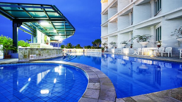 A swimming pool with a glass canopy, stone tiles, and potted plants. - Hotel Sahid Jaya Makassar City Centre (Makassar)