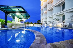 A swimming pool with a glass canopy, stone tiles, and potted plants.