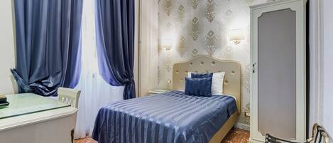 A hotel room with a bed, a desk, a chair, and a wardrobe.