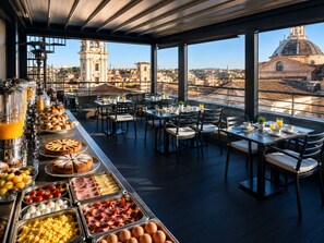 Un bufé de desayuno con diversas opciones de comida y vistas a un paisaje urbano.