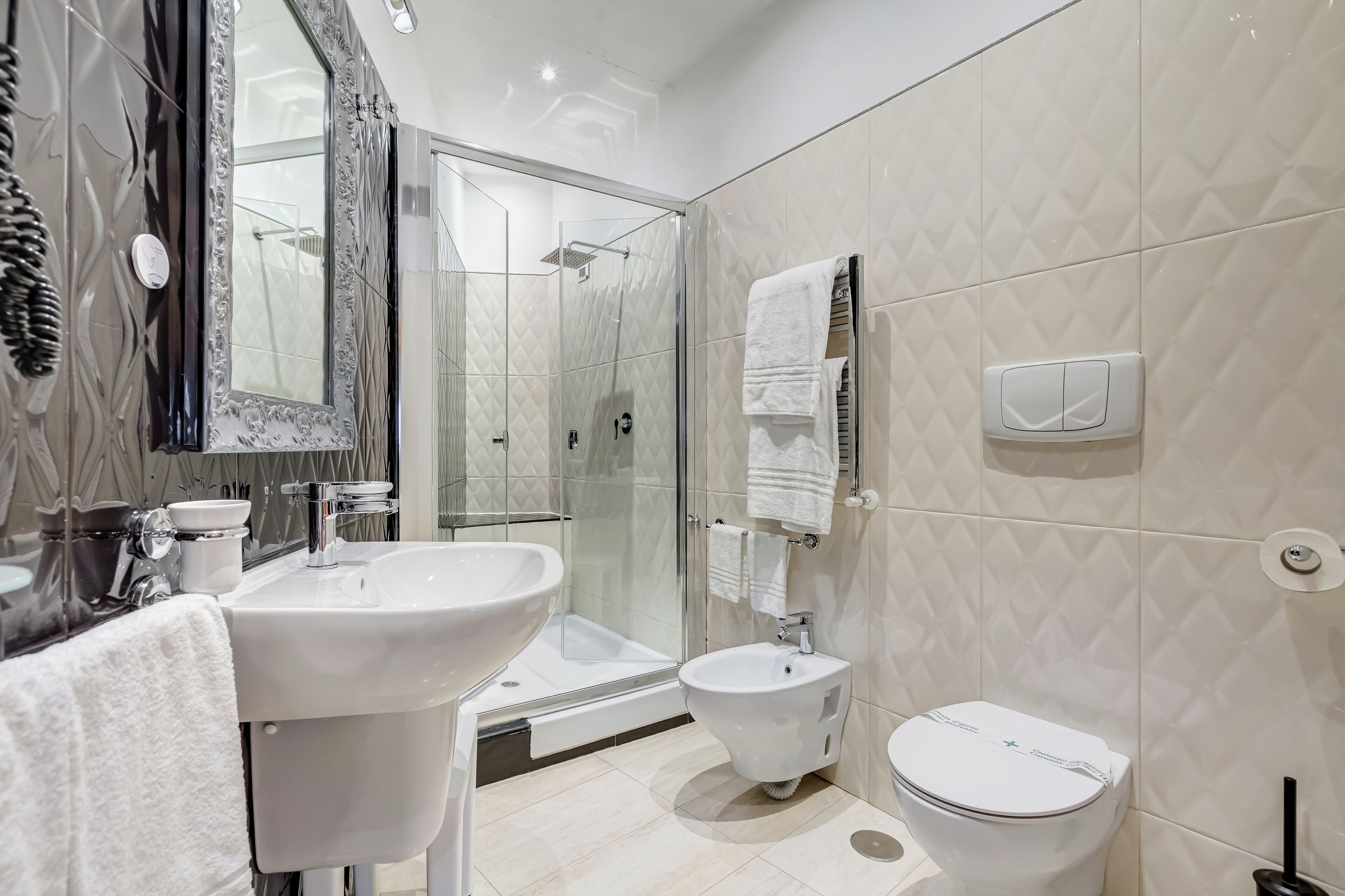 Un baño moderno con ducha de vidrio, un bidé, inodoro y lavamanos.