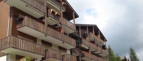 A multi-story building with wooden balconies and a modern architectural design.