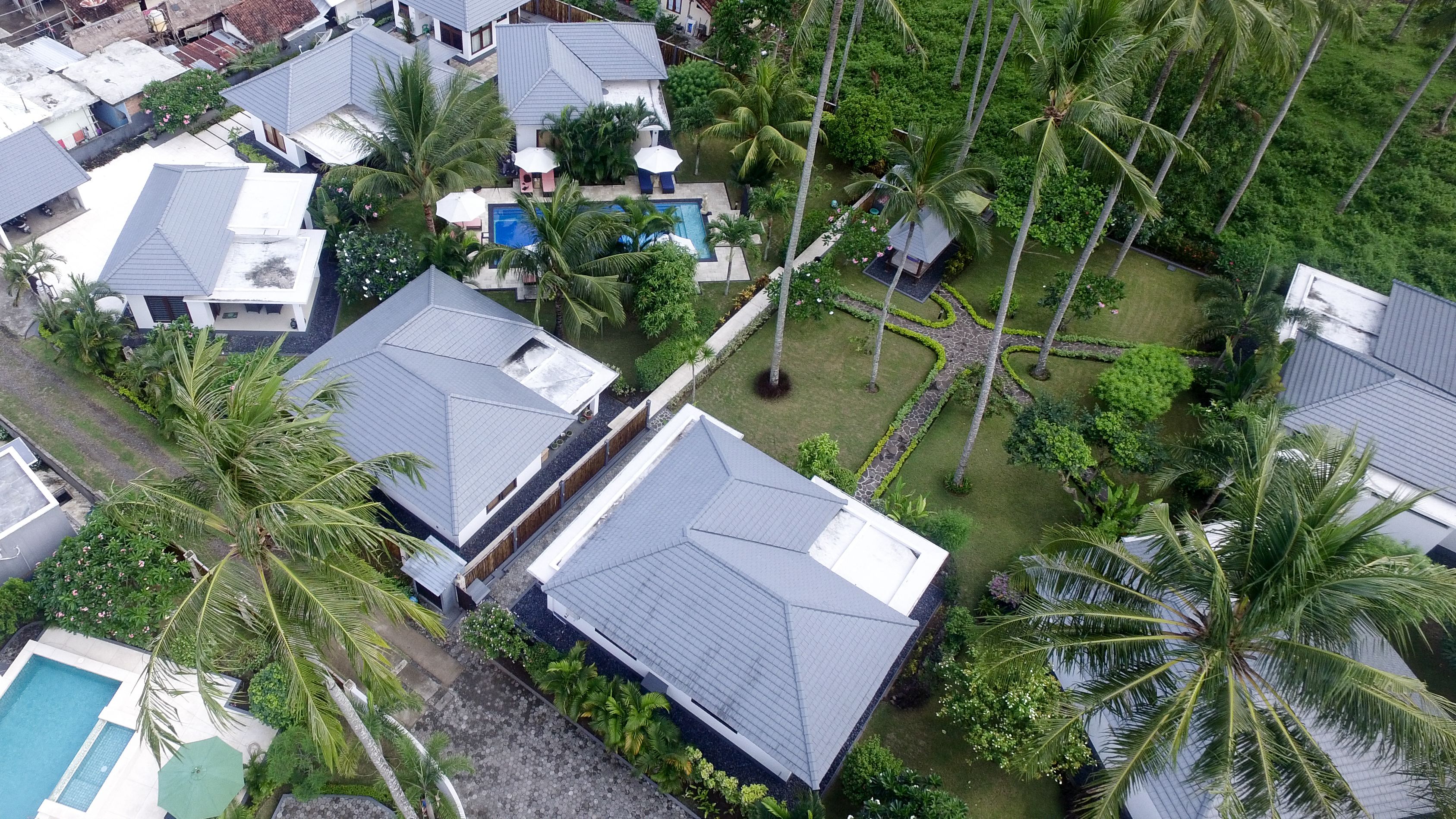Vue aérienne d’un quartier résidentiel avec de nombreuses maisons, une piscine et des palmiers.