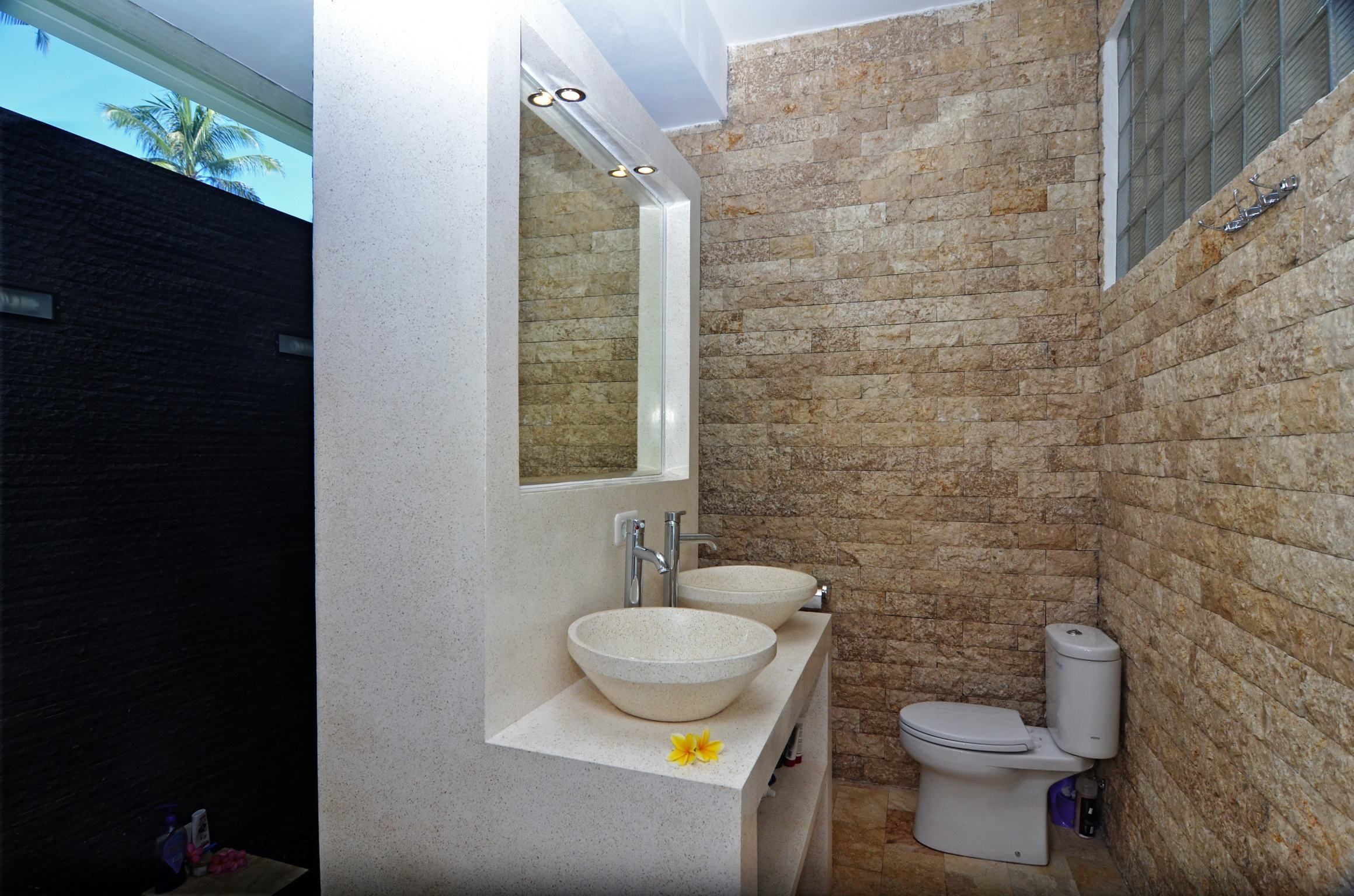 Ein Badezimmer mit einem großen Spiegel, zwei Waschbecken und einer Toilette.