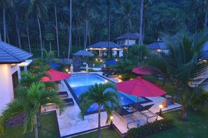 Un resort con piscina, mobiliario exterior y palmeras.