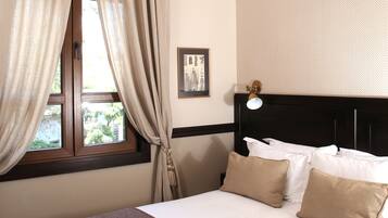 Quarto com uma cama grande, janela com cortinas, um quadro na parede e luminária no teto.