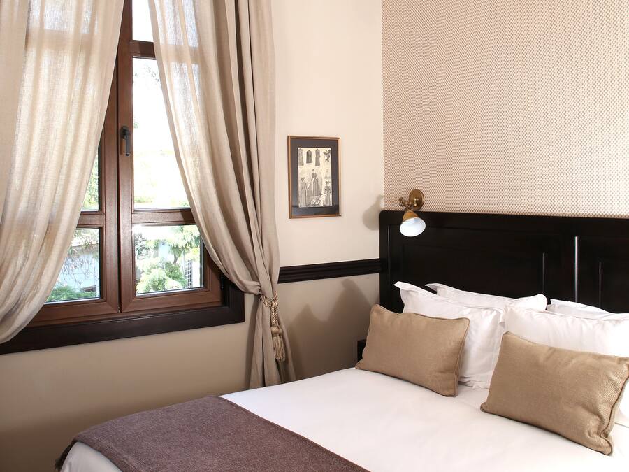 Quarto com uma cama grande, janela com cortinas, um quadro na parede e luminária no teto.