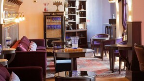 Een ruime woonkamer met een weelderige kroonluchter, een comfortabele bank en een boekenkast.