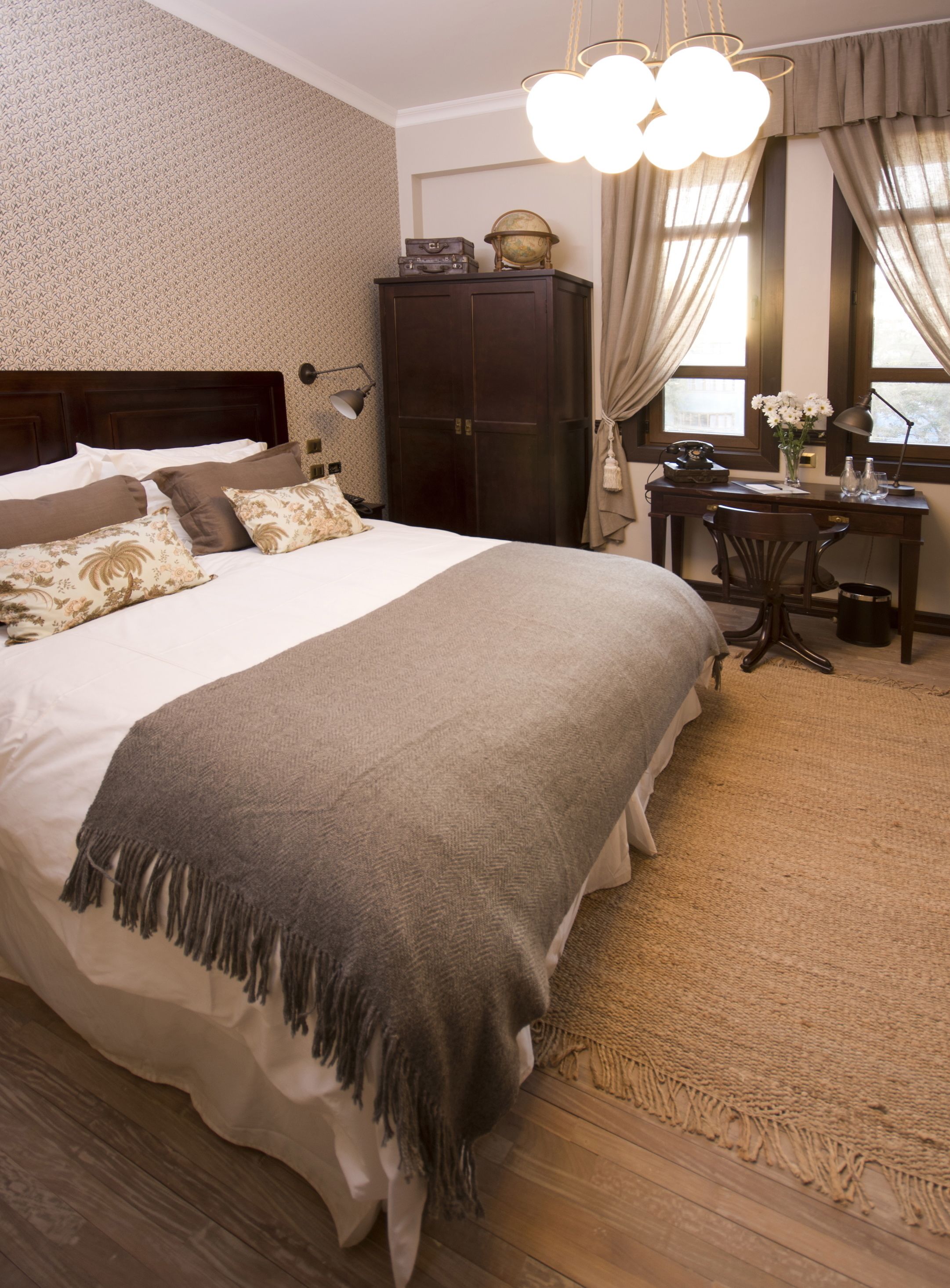 Une chambre bien rangée, avec un grand lit, un bureau en bois et une armoire.
