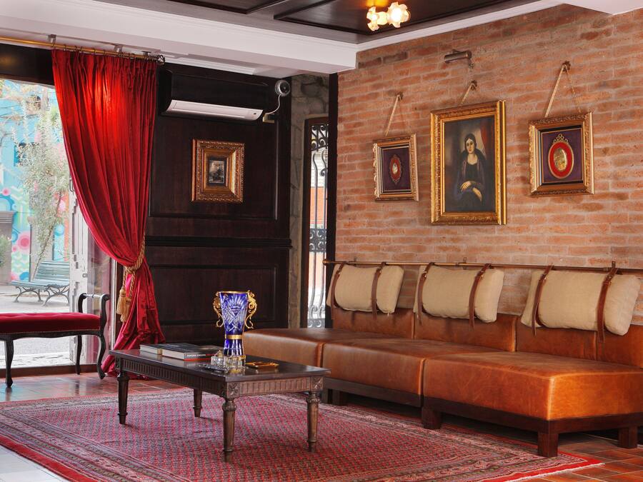 Una habitación con una cortina roja, un sofá, una mesa y cuadros en la pared.