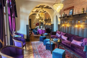 Un'accogliente hall con divani viola, poltrone blu e un tappeto decorato.