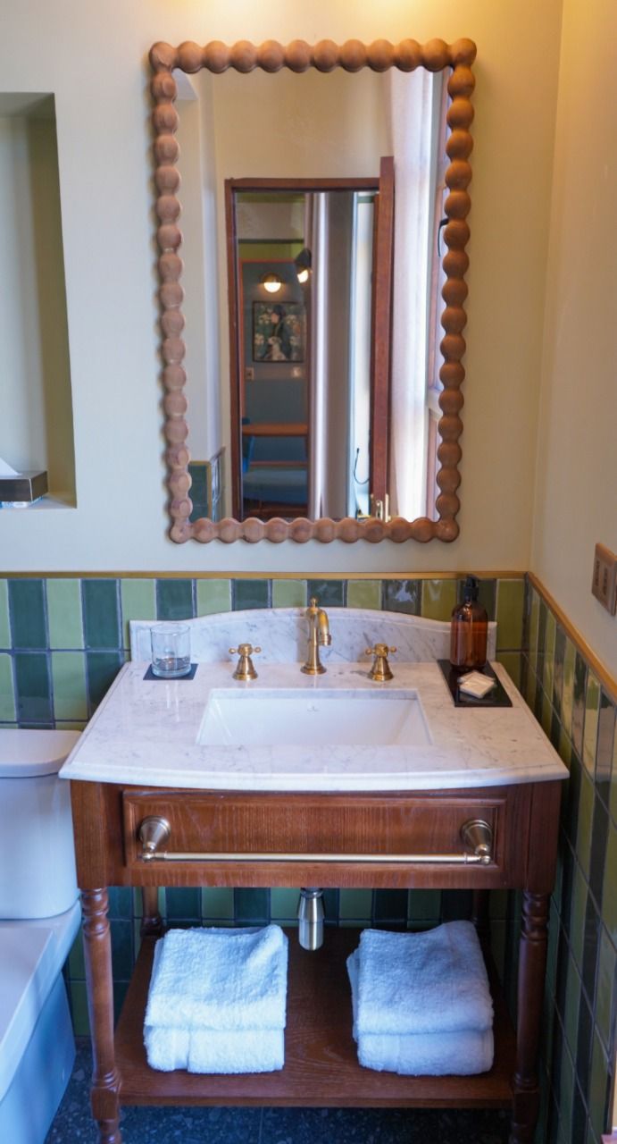 A bathroom with a wooden vanity, a large mirror with a wooden frame, and a marble sink.
