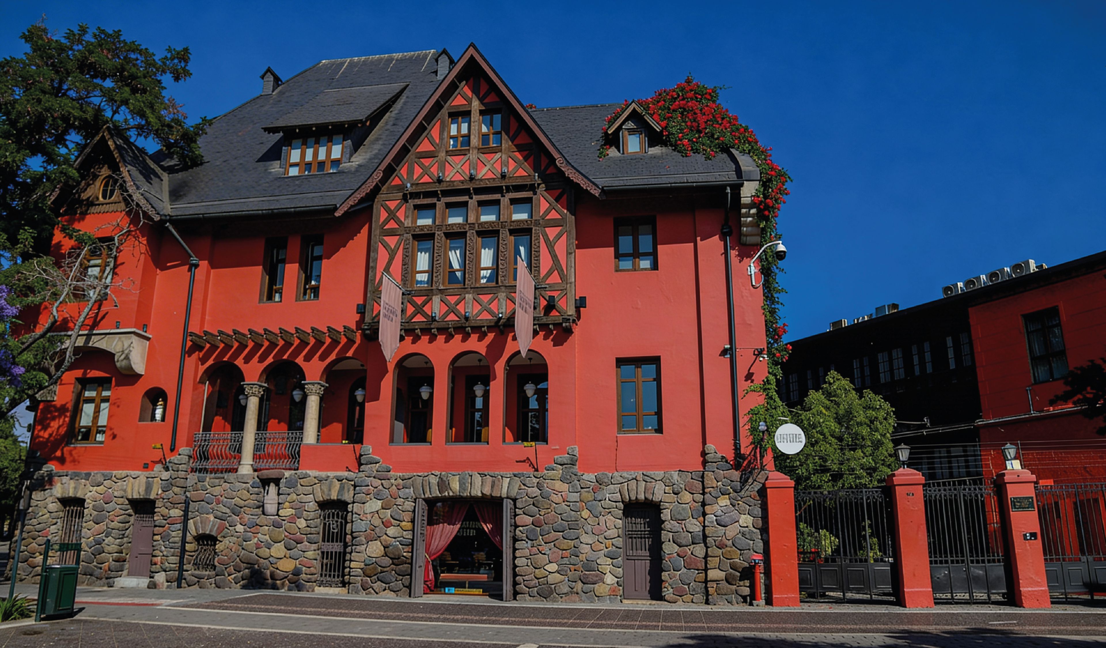 A red building with a stone facade, multiple windows, and a balcony.