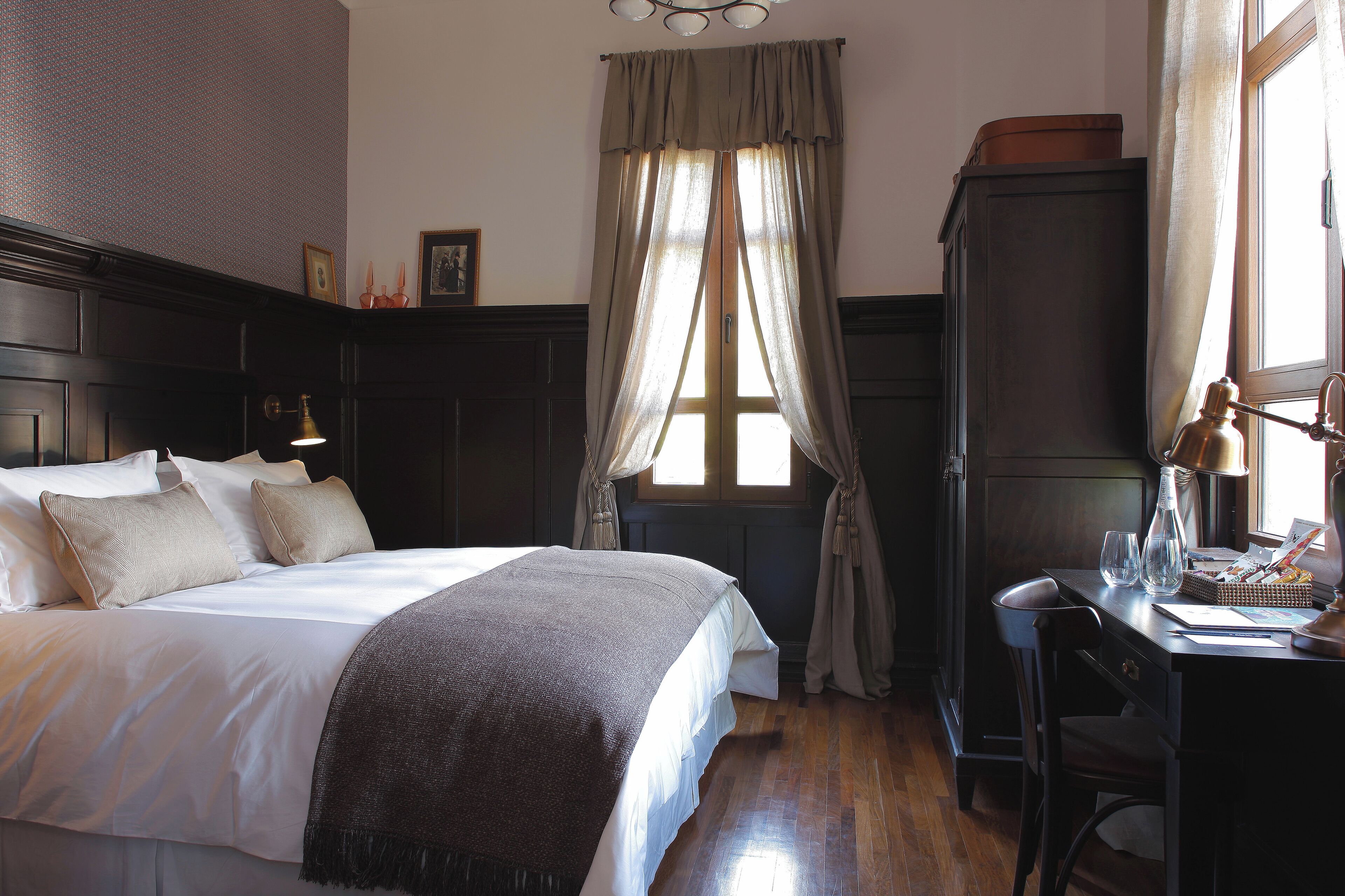 A bedroom with a bed, a desk, and a wardrobe.