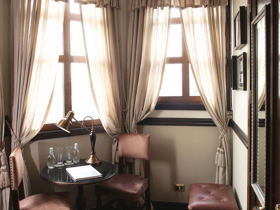 Una habitación de esquina con suelo de madera, una mesa redonda con sillas, un banco y una lámpara colgante.