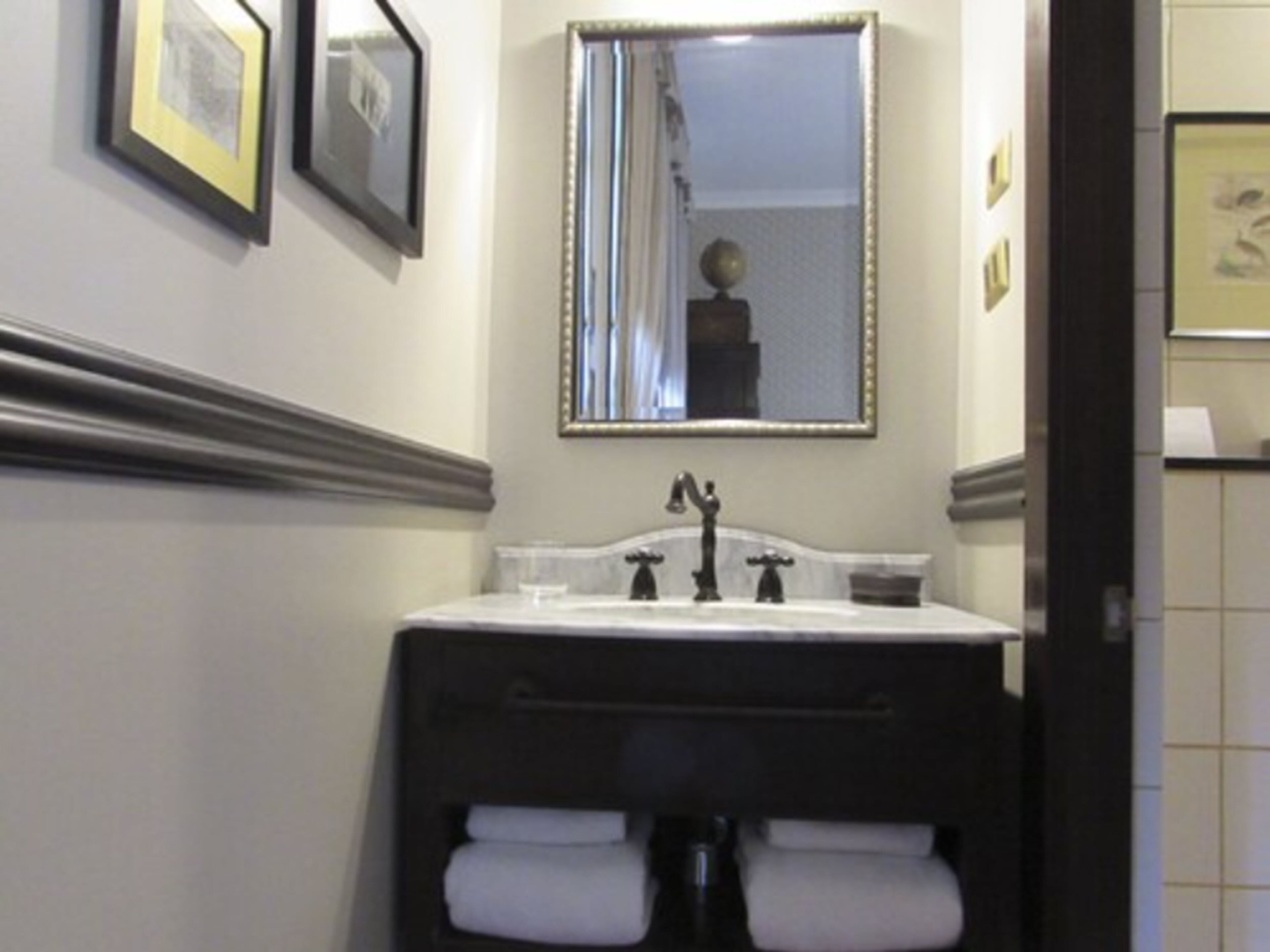 A bathroom with a white sink, a mirror above it, and two towels hanging from a towel rack.