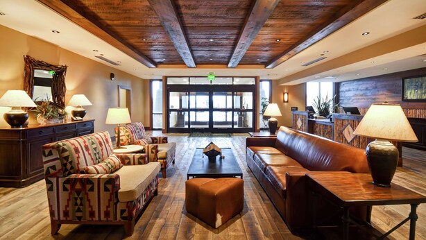 A spacious lobby with a high ceiling, wooden beams, and a central seating area with sofas and a coffee table.