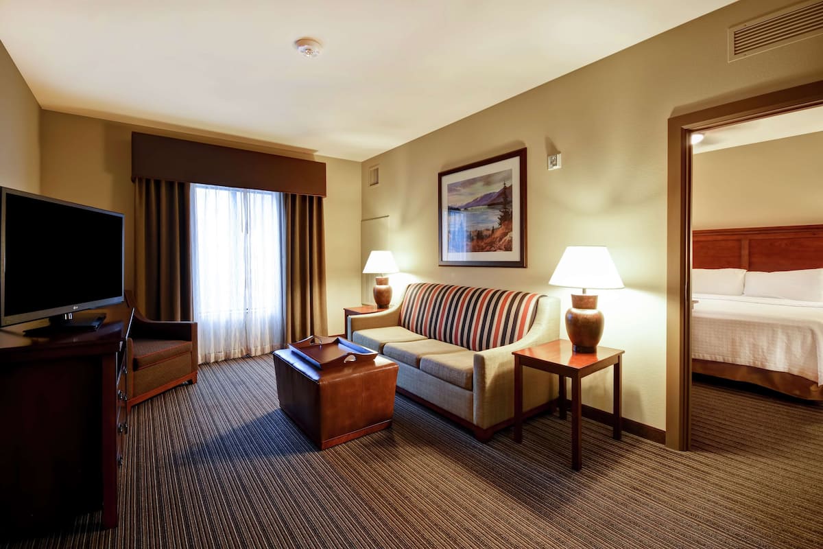 A hotel room with a sofa, a TV, a lamp, and a bed.