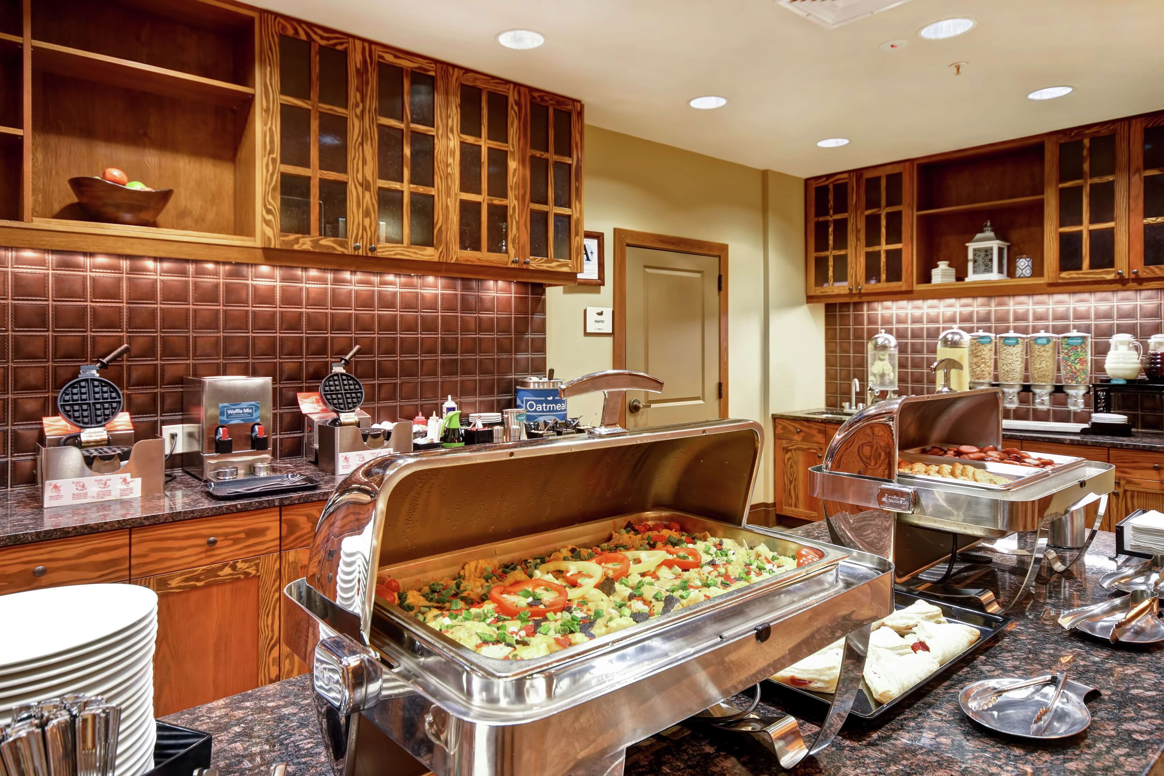 Un buffet avec une variété de plats et d’ustensiles, des armoires en bois et un mur recouvert de carreaux.