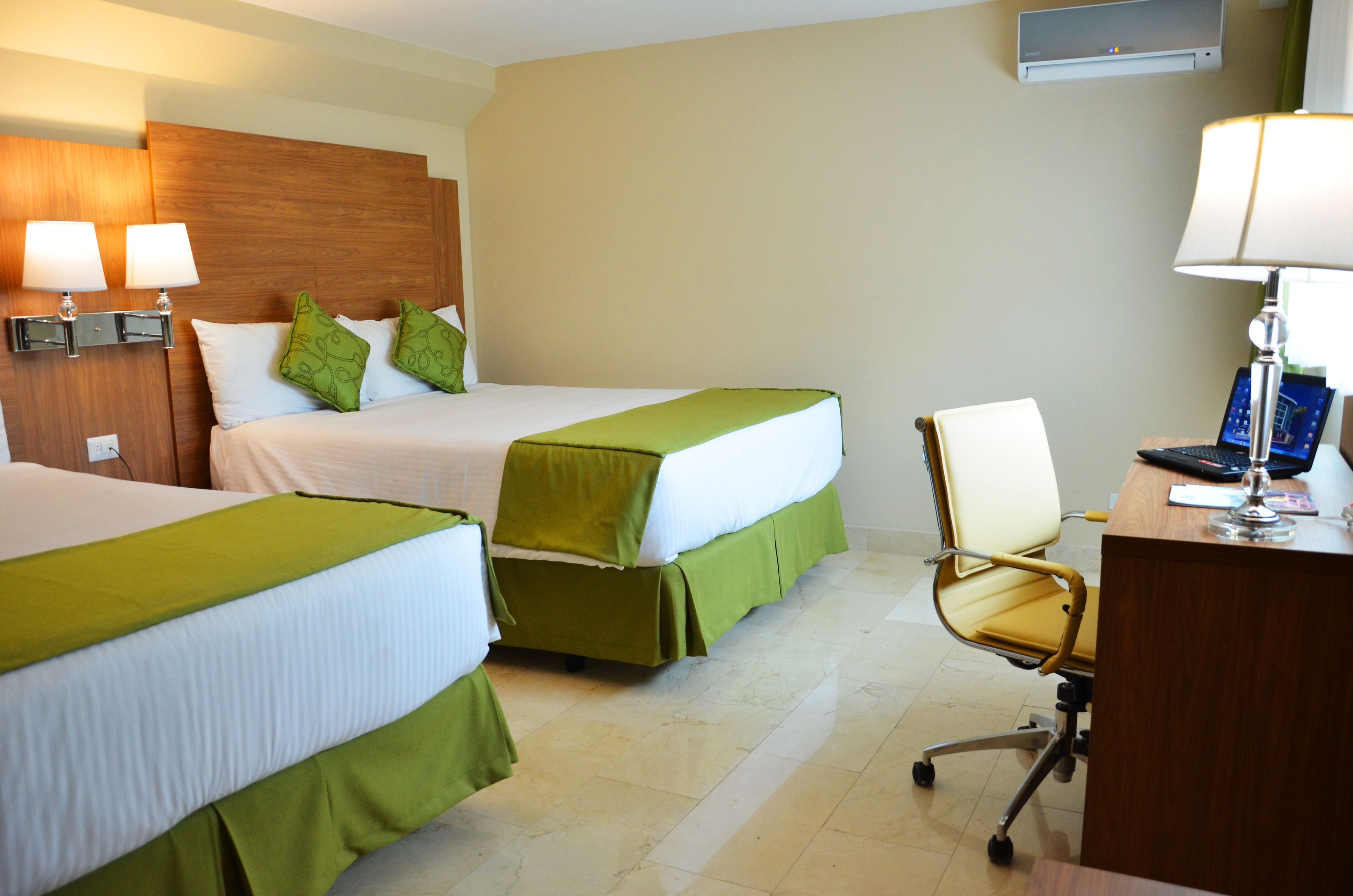 Una habitación de hotel con dos camas, un escritorio, una silla y un televisor.