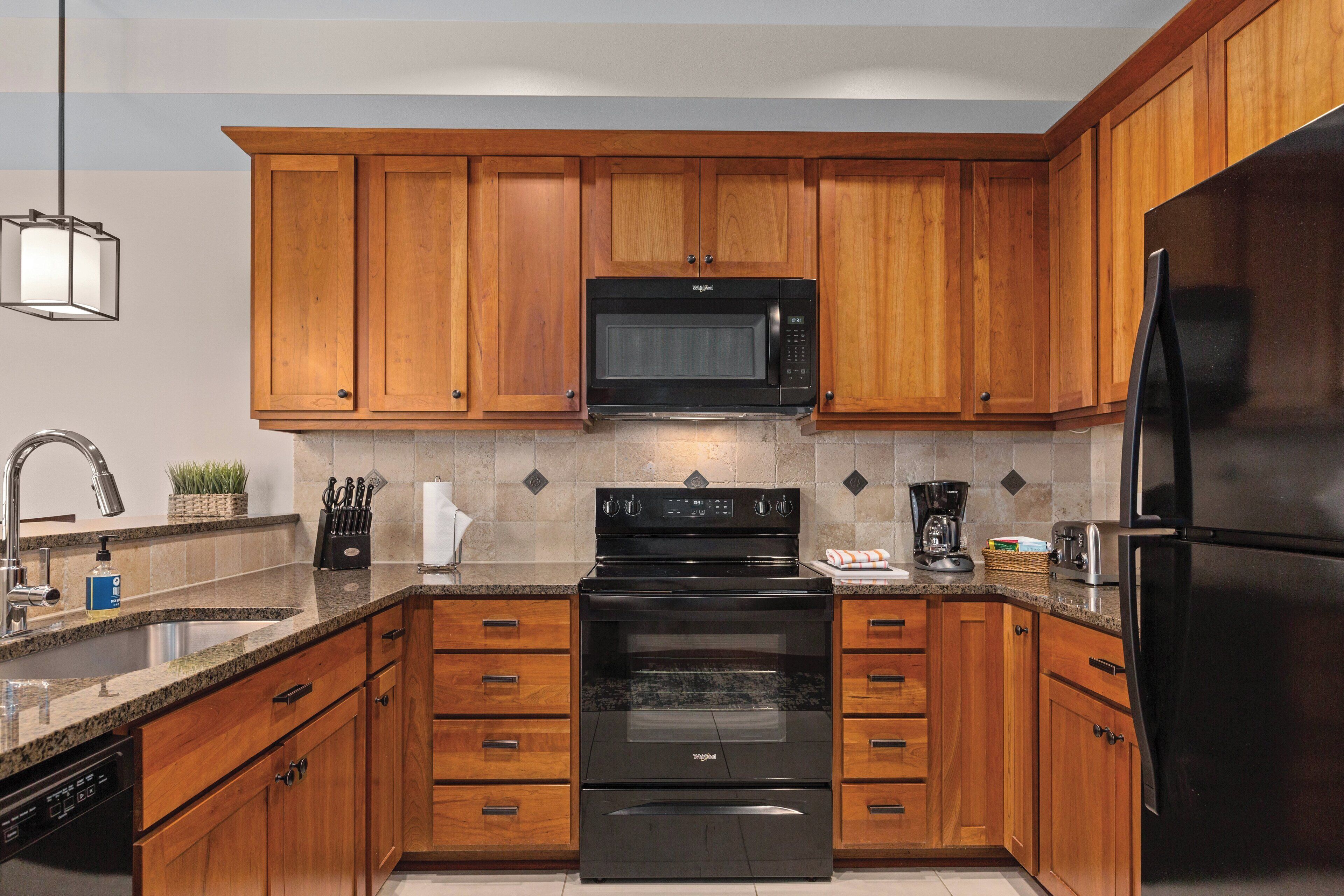 A modern kitchen with wooden cabinets, a stainless steel refrigerator, a built-in microwave, and a dishwasher.