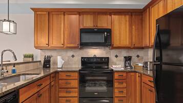 A modern kitchen with wooden cabinets, a stainless steel refrigerator, a built-in microwave, and a dishwasher.