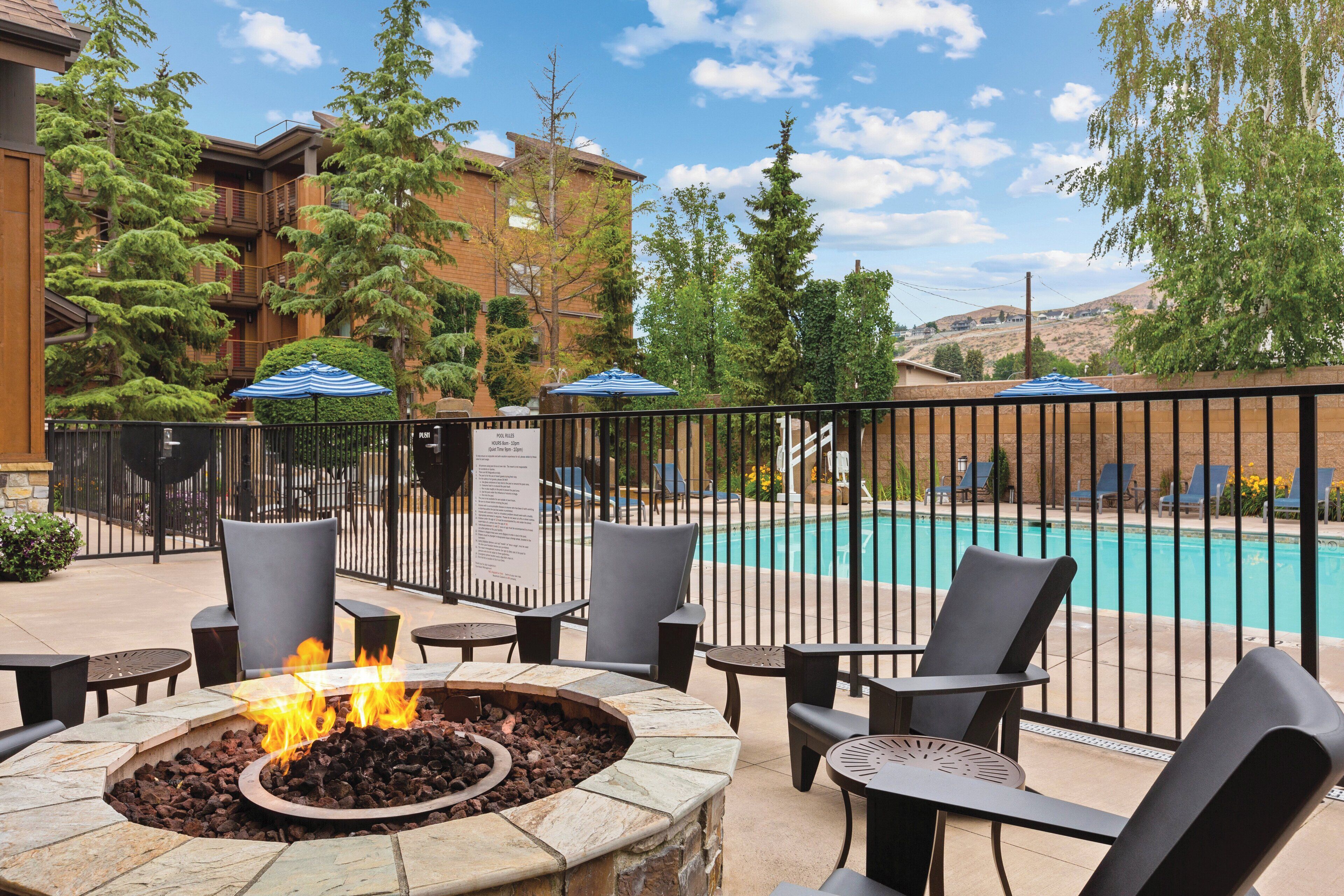 An outdoor seating area with a fire pit, pool, and a view of a mountain.