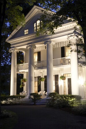 A large, two-story house with a grand entrance, large columns, and a balcony. - The Inn At Cape Cod (Yarmouth Port)