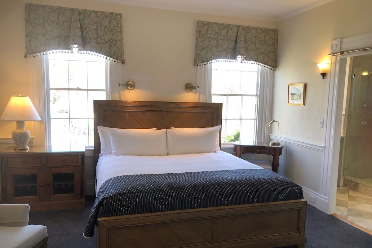 A neatly arranged bedroom with a wooden bed, two bedside tables, a lamp, and a framed picture on the wall.