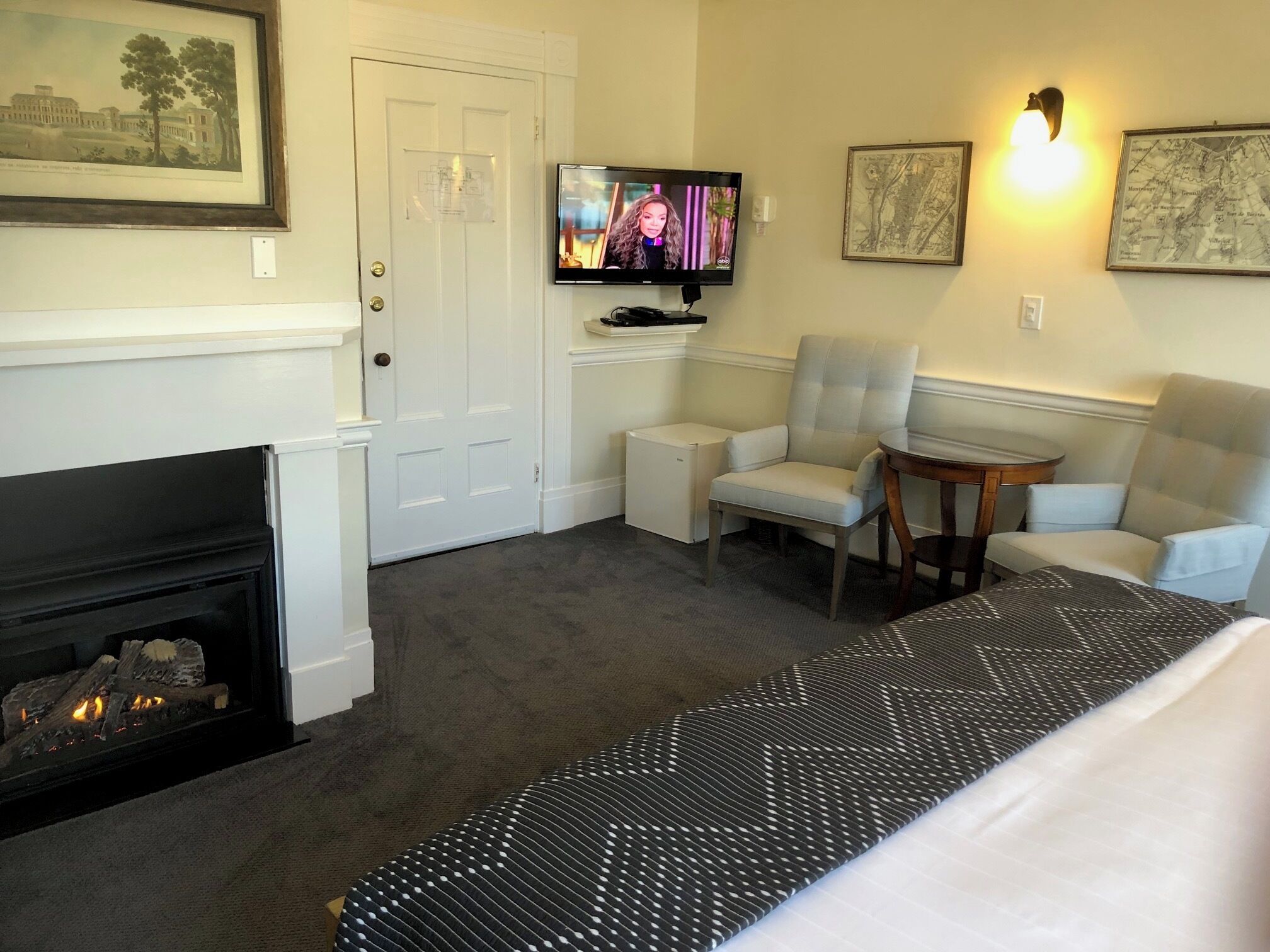 A hotel room with a fireplace, a television, a sofa, and a small table.