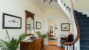 Un couloir avec une commode en bois, un miroir et des tableaux encadrés accrochés au mur.