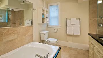 A modern bathroom with a large bathtub, a toilet, and a shower.