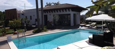 Una piscina al aire libre de temporada, sillones reclinables de piscina