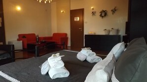 Een hotelkamer met een bed, een rode bank, een klein tafeltje en een open haard.